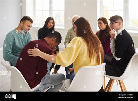 Diverse People Supporting And Comforting Crying Young Man In Group