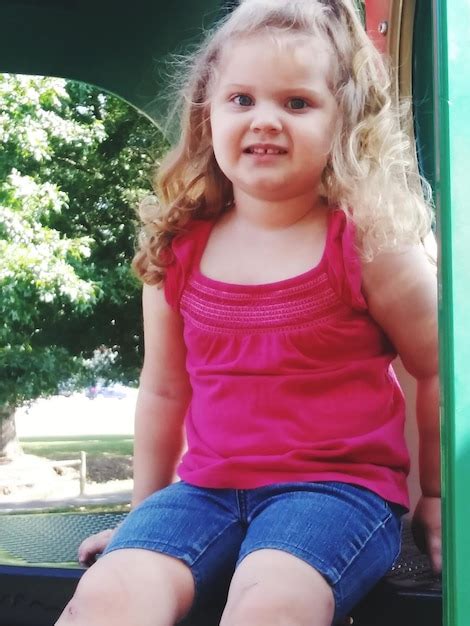 Premium Photo Portrait Of Smiling Girl Sitting Outdoors