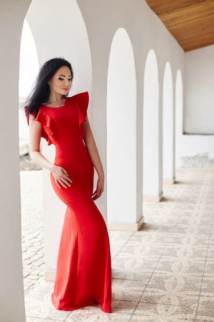 Premium Photo Sexy Brunette Woman In Red Dress Stands Near The Walls