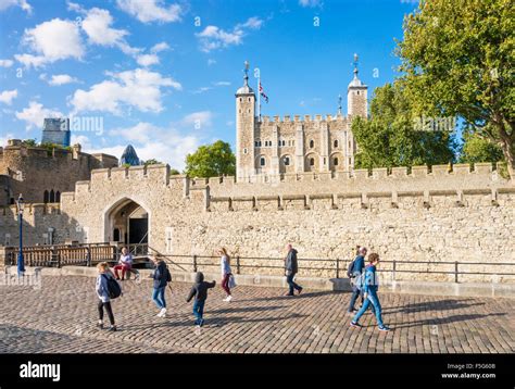 People walking past the castle walls and white tower Tower of London ...