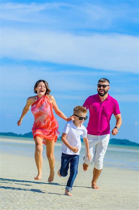 Famille De Trois Fonctionnant Le Long Du Temps De Plage De Rire Et