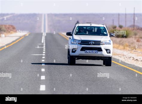 White Toyoya Hilux Pick Up Truck Driving Along A Very Straight And Long