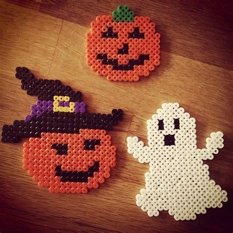 Two Halloween Coasters Made Out Of Perler Beads On A Wooden Table With