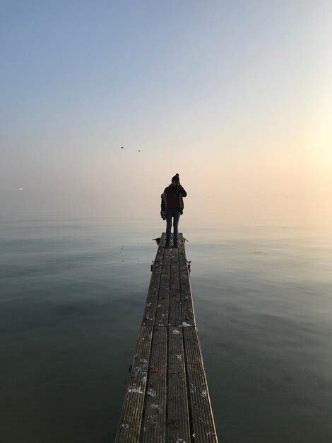 Premium Photo Man Standing On Pier At Sea Against Clear Sky