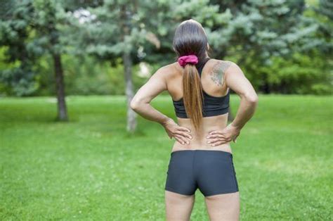 A Woman Standing In The Grass With Her Back To The Camera And Holding