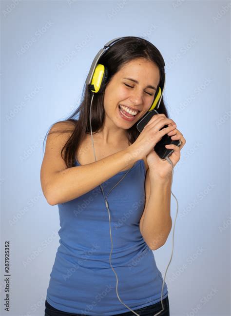 Beautiful Young Woman In Headphones Listening To Music On Mobile Phone Dancing And Singing Stock