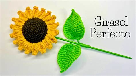 A Crocheted Sunflower And Green Leaves On A White Surface