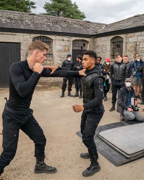 Two Men Fighting Each Other In Front Of A Group Of People Wearing Facemasks