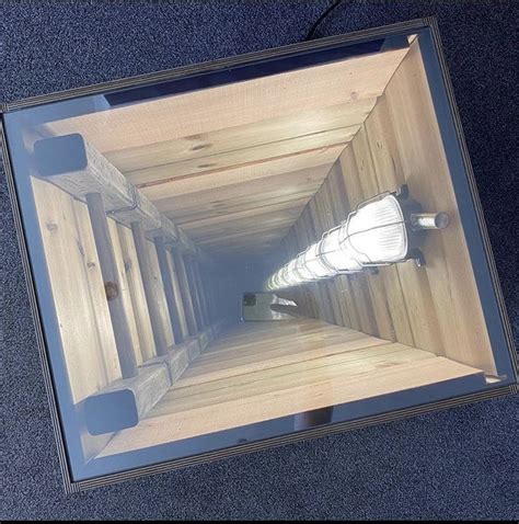 The Reflection Of A Light Bulb In A Glass Box On The Floor Is Seen From