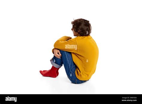 Portrait Of Young Boy Sitting On Floor In Depression Hugging Legs Over