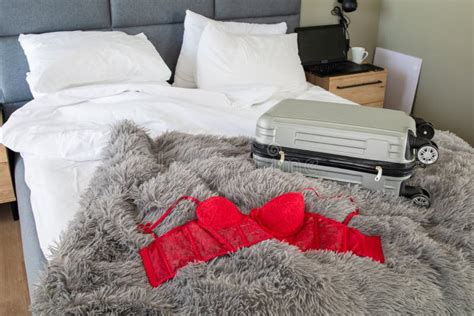 The Red Lingerie With Luggage Travel Bag On White Bed Of Hotel A