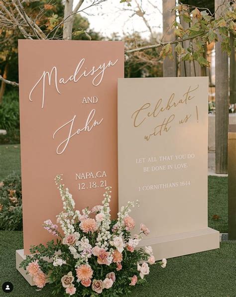 Two Wedding Signs With Flowers In Front Of Them