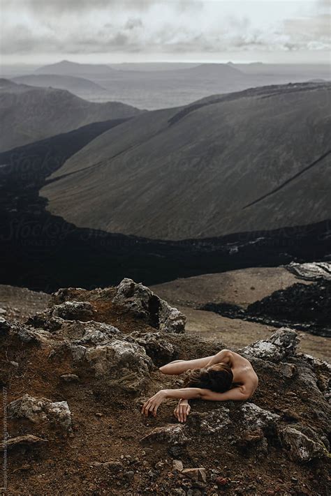 Nude Woman Lying On Her Arms In Front Of Black Lava River In Iceland