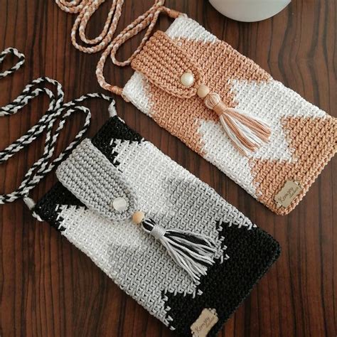 Two Crocheted Purses Sitting On Top Of A Wooden Table Next To A Cup