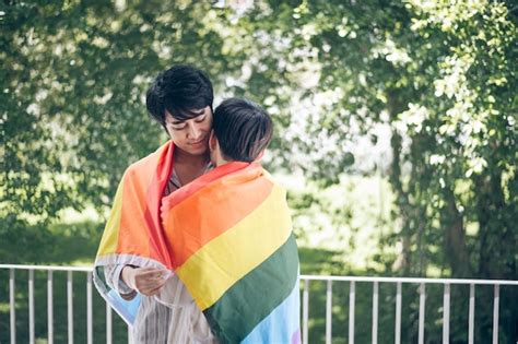 Premium Photo Gay Men Embracing With Flag While Standing By Railing Against Trees
