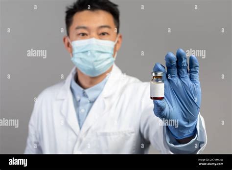 Serious Mature Chinese Man Doctor In White Coat Protective Gloves