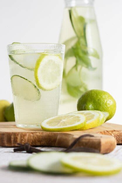 Garrafa de limonada e um copo servido rodelas de limão e pepino