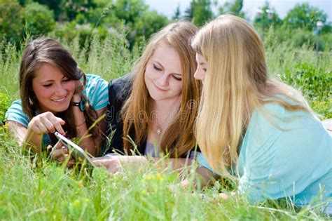 Trois Jeunes Filles De Blonde Et De Brune L Aide Du Comprim Photo Stock Image Du Regarder