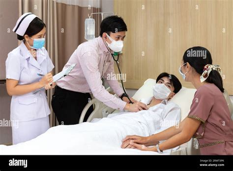 Asian Doctor Using Stethoscope Listening Heartbeat Of Patient And Nurse
