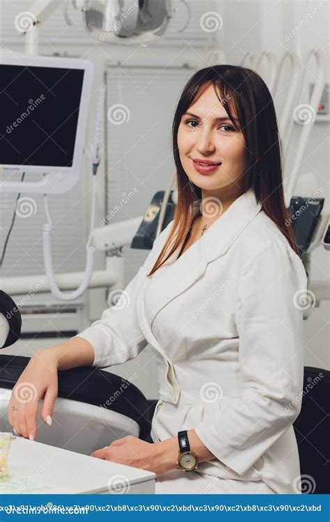 Portrait Of Attractive Smiling Female Dentist With Hands Folded Stock