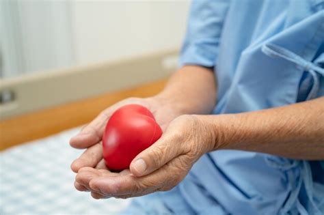 Paciente idosa asiática segurando coração vermelho na mão na cama no