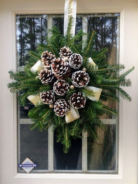 a wreath with pine cones and bows is hanging on the front door's window