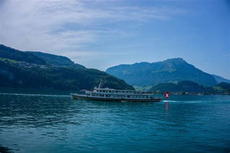 A Boat Traveling On The Water With Mountains In The Background