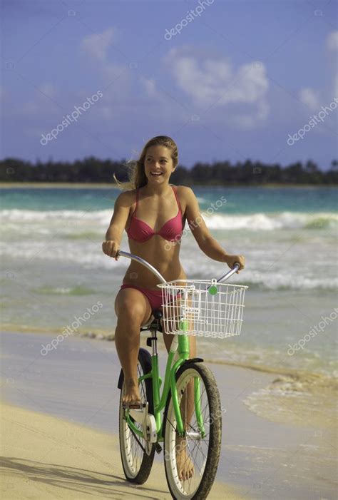 Blond Girl In Bikini Riding Her Bike On The Beach Stock Photo