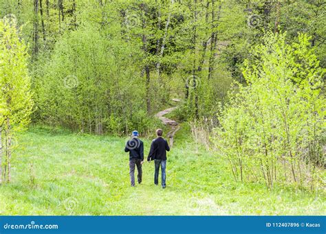 Dos Hombres Que Caminan En Camino Doblado En El Bosque Foto De Archivo