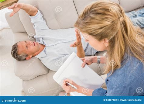 Depressed Man Lying On Couch And Talking To Therapist Stock Photo