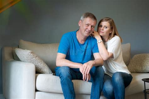 Happy Caucasian Couple Laughing While Sitting On Sofa In Living Room