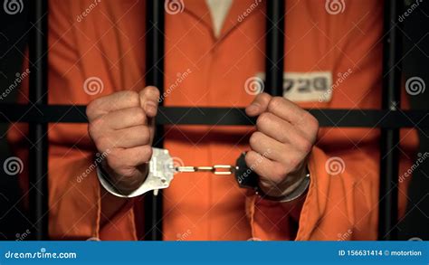 Convicted Man Showing Handcuffs Standing Behind Prison Bars