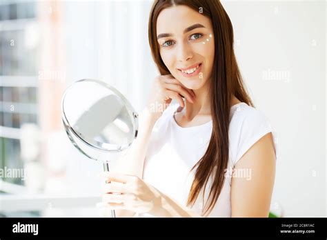 Facial Skin Care Young Woman Applies Face Cream In The Spacious