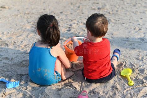 Brother And Sister In Bathing Suits Playing With Beach Toys In The Sand