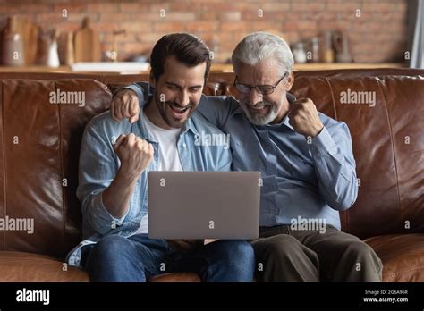 Happy Excited Grown Son And Mature S Father Using Laptop Stock Photo Alamy