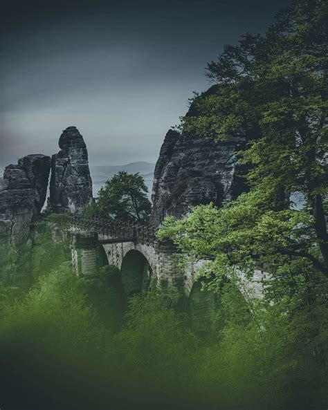 An Image Of A Bridge In The Middle Of Some Trees And Rocks That Look