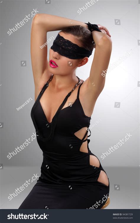 Attractive Brunette Girl In A Black Dress Sitting Blindfolded With Her Hands Tied Stock Photo