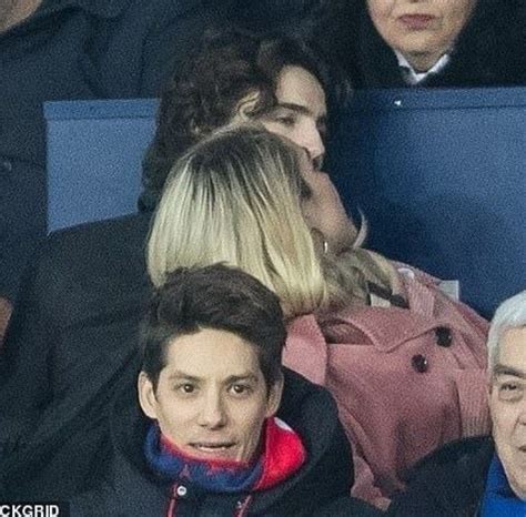 Two People Sitting Next To Each Other In The Stands At A Soccer Game