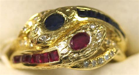 A gold, ruby, sapphire and diamond set ring designed as two conjoined ...