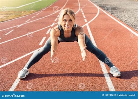 Sporty Lifestyle Young Woman On Stadium Legs Aside Stretching On Track