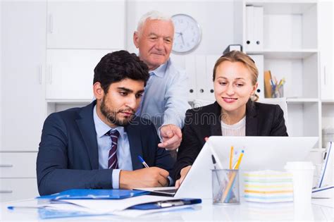 Employees Are Demonstrating Reports On Laptop To Mature Boss Stock