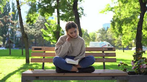 Girl Sitting on a Bench in the Park and Reading Book. Stock Footage ...