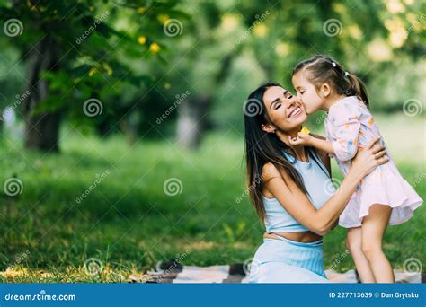 Mother And Daughter Lying On The Lawn Daughter Kiss Her Mother On The