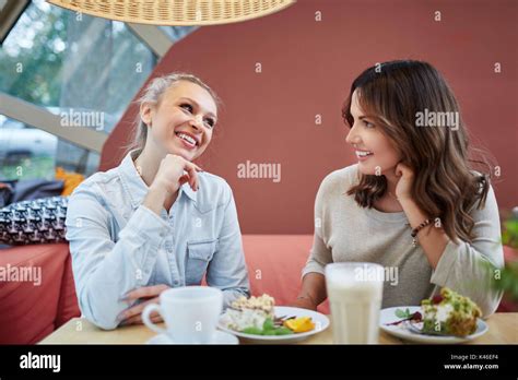 Portrait Of Two Women Friends Talking Over A Coffee And Dessert Stock