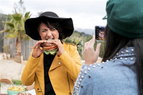 Amigo Tomando Fotos De Mujer Comiendo Hamburguesa Foto Gratis