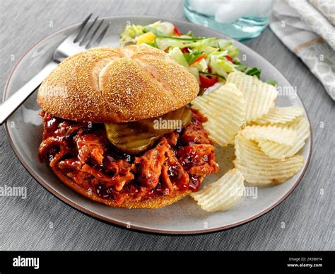 Shredded Bbq Pork With Pickles On A Kaiser Roll Bun Served With Potato