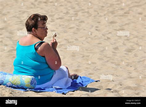 Obese Woman In Summer Eating Ice Cream On Beach Along The North Sea