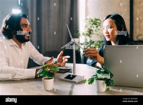 Mature Businessman Discussing With Colleague Over Wind Turbine Model