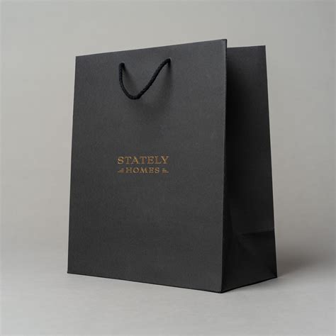 A Black Paper Bag With Gold Lettering On The Front That Says Safely