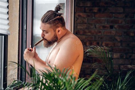 Homem Farpado Que Fuma Um Charuto Na Frente Da Janela Foto De Stock